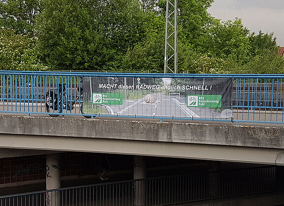 RS1-Banner an Bahnbrücke über B233