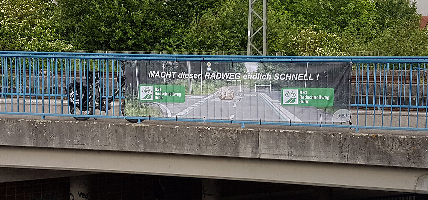 RS1-Banner an Bahnbrücke über B233