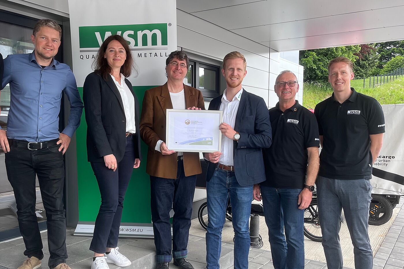 Zertifikatsübergabe (Gold) an WSM – Walter Solbach Metallbau GmbH, Waldbröl am 22. Mai 2024 v.l. Rudolf Bergen (Mobilitäts- und Klimaschutz-Manager Stadt Waldbröl), Larissa Weber (Bürgermeisterin Stadt Waldbröl), Andreas K. Bittner (ADFC / "Fahrradfreundlicher Arbeitgeber"), Christoph Solbach (Geschäftsführer WSM), Andreas Hombach (Betrieblicher Mobilitätsmanager, IHK, WSM) und Rico Henseleit (Radverkehrskoordinator, WSM).