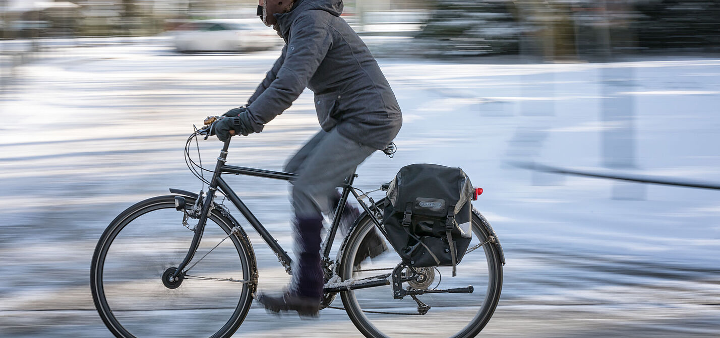 Ein Radfahrer auf einer winterlichen Straße mit Schnee.