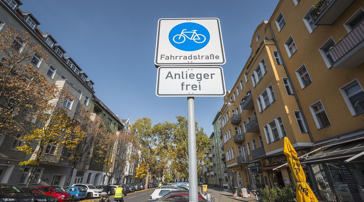 Blick auf ein Verkehrszeichen "Fahrradstraße" am Eingang einer Straße mit Wohnhäusern auf beiden Seiten. 